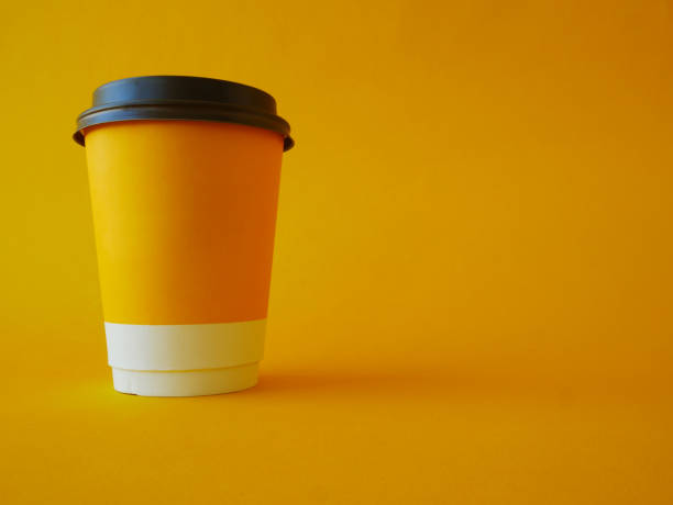 istock A yellow paper disposable cup with a black plastic lid on a yellow background with 1405806799
