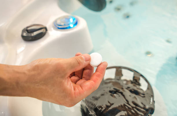 Using Chlorine Tabs in a Hot Tub Spa Caucasian Men Using Chlorine Tabs in a Hot Tub Spa to Maintain Healthy and Quality Water in the Bathtub. hot tub stock pictures, royalty-free photos & images