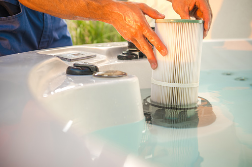 Técnico de bañera de hidromasaje que retira el filtro de agua y realiza el mantenimiento programado del SPA de jardín photo