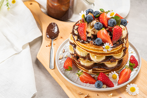 Pancakes with chocolate paste and hazelnuts, banana, strawberry and blueberry