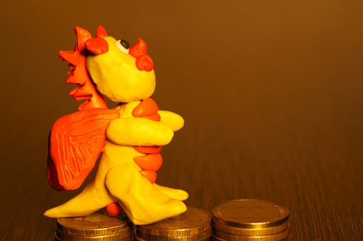 A dragon figurine and a stack of coins on the table.