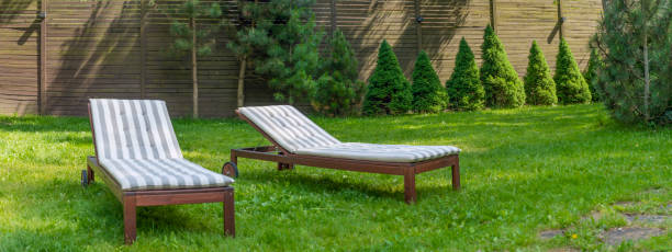 istock Lounge chairs on the backyard in a beautiful garden. Two empty sunbeds on the grass. 1405812087