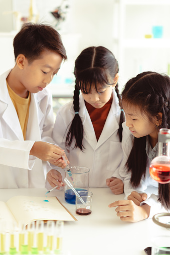 Young Primary Middle Students in Science Class with a glass beaker learning STEM.