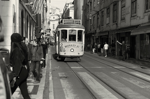 Lisbon, Portugal - April 2, 2022: A traditional tram runs across a street in Lisbon downtown.