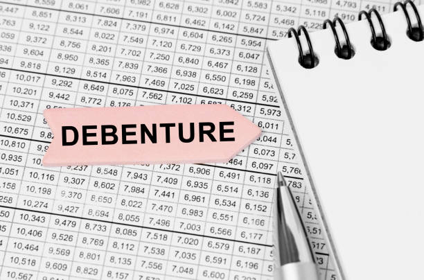 istock On the table among the reports is a notebook, a pen with an arrow with the inscription - Debenture 1405818564