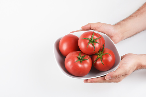 Hand holding tomato bowl on the white background
