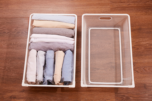A basket with neatly folded piles of clothes and an empty laundry basket. The concept of washing, organization of order, general cleaning.