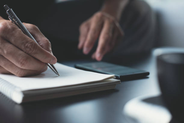istock Man hand writing notes on notebook and surfing internet on mobile phone on table 1405821871