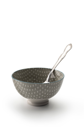 Empty ceramic bowl with spoon on white background