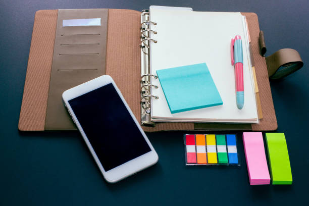 istock Blank ring binder planner with index tabs, mobile phone and note pads use for time management in personal or business. 1405828207