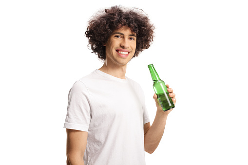 Cheerful caucasian guy with curly hair holding a bottle of beer and smiling isolated on white background