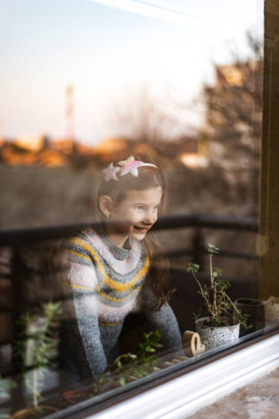istock Smiling loving young girl looking through a window 1405830763