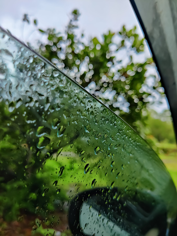 Water drops in an open car glass window in a rainy day
