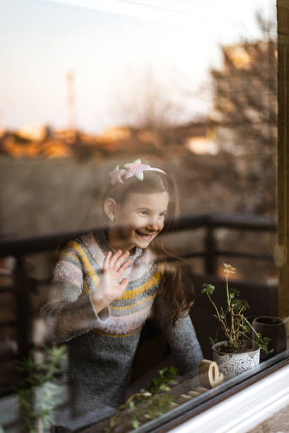 istock Smiling loving young girl looking through a window 1405831282