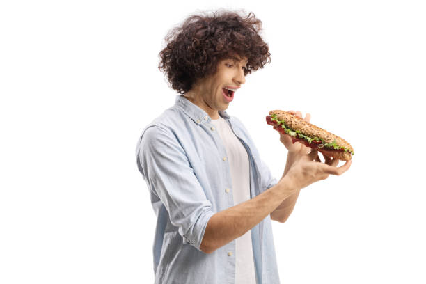 istock Young man with a curly hair holding a baguette sandwich 1405831907