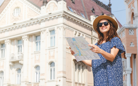 Pregnant woman in sunglasses and sun hat traveling with map.