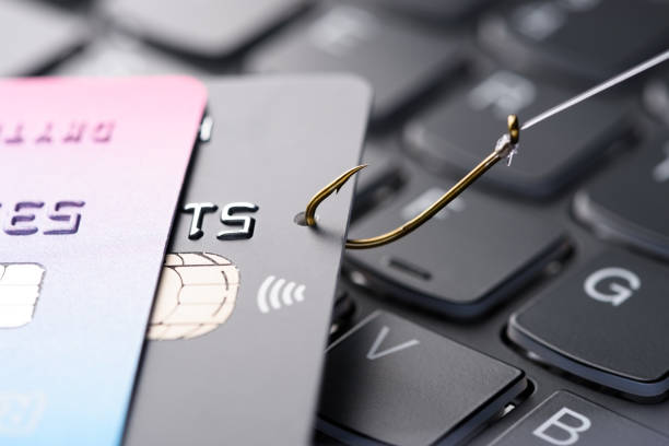 Credit card on fishing hook pulled from stack on keyboard stock photo