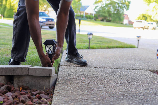 A black African-American man installing a solar  landscaping light in a lawn