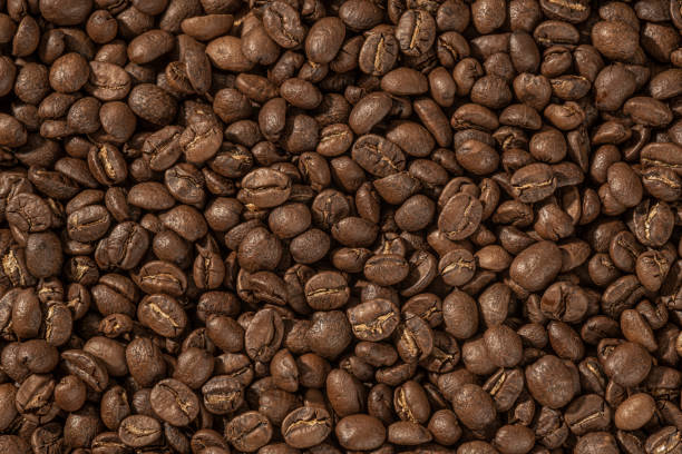 Roasted coffee beans closeup. Background, Coffee grains scattered on the table, with copy space for your text.