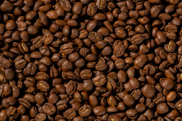 istock Roasted coffee beans closeup Background, Coffee grains scattered on the table, working hours coffee, hot drinks. 1405839514
