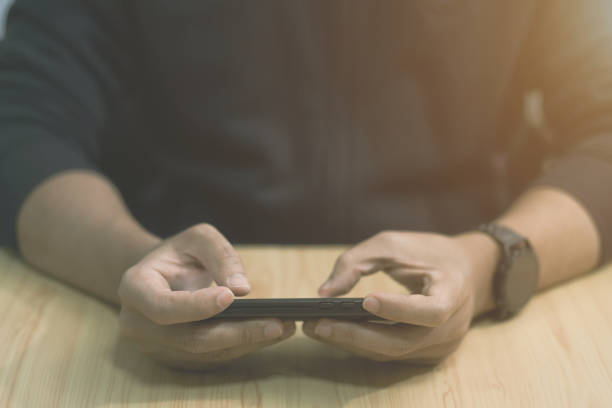 istock hand hold mobile cell phone device, holding mobile phone playing video stream online, playing videogames on cell phone in the evening 1405839683