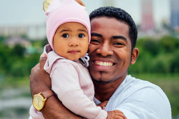 ojciec afro przytula swoją córkę mieszanej rasy, spędzając czas w ogrodzie - male men black african descent zdjęcia i obrazy z banku zdjęć