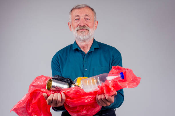 istock old caucasian male holding plastic trash in studio white background 1405840377