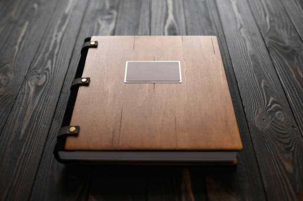 un vieil album photo avec une couverture en bois et un bouclier sur une table rustique. logo gratuit - book book cover old leather photos et images de collection