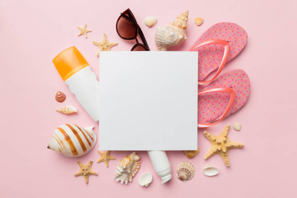 istock Summer time concept with blank greeting card and blank white paper on colored background. Seashells from ocean shore in the shape of frame separated with space for text top view 1405841833