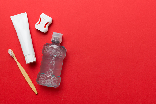 Mouthwash and other oral hygiene products on colored table top view with copy space. Flat lay. Dental hygiene. Oral care products and space for text on light background. concept.