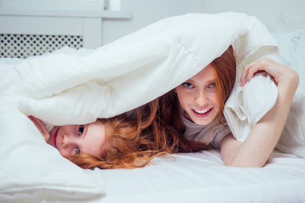 istock two happy redhaired ginger girls playing hide and seek under white blanket. self-isolation corona virus outbreak concept 1405841931