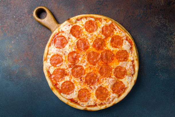istock Pepperoni pizza on wooden board on blue concrete table top view 1405841981