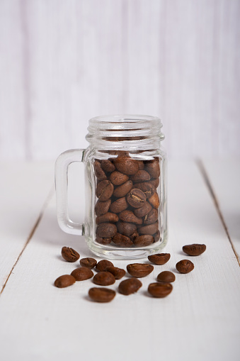 Natural roasted coffee beans in a small transparent glass jar