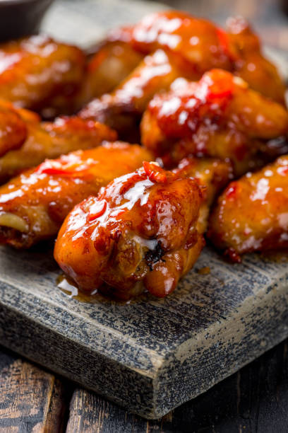 Chicken wings in sweet chili mango sauce extreme macro close up vertical Chicken wings in sweet chili mango sauce extreme macro close up vertical sticky sesame chicken sauces stock pictures, royalty-free photos & images