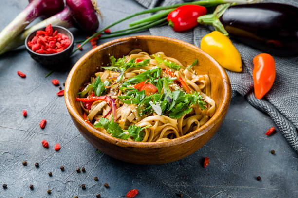 istock Udon noodles with vegetables on wooden bowl on grey table 1405842265
