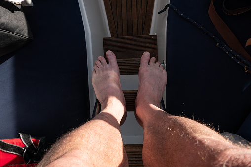 A man's legs on a small ladder on a boat.