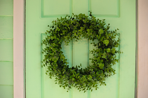 Autumn welcome wreath, decorating front door home. House door with decor with leaves wreath. Autumn cozy decor home for thanksgiving. Summer Decor door. Close Up of green door and decorative wreath.