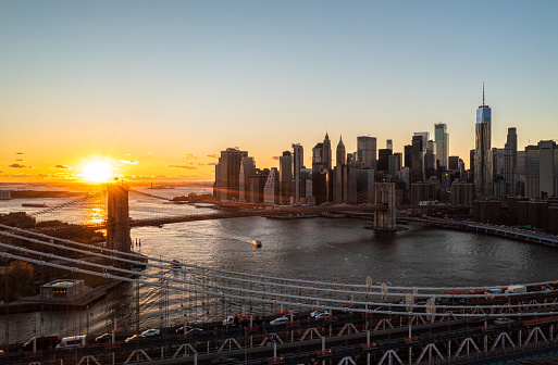 Manhattan and Brooklyn Bridges against golden sunset. Aerial scenic shot of group of modern skyscrapers. Manhattan, New York City, USA.