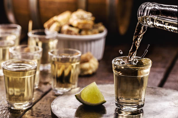 glass of cachaça, pinga, cana or caninha is the sugar cane brandy, typical drink from brazil, drops of drink flying, spilling or overflowing, filling the glass - shot glass glass alcohol color image imagens e fotografias de stock