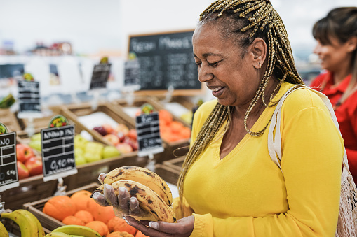 African senior woman buying fresh organic fruits inside supermarket