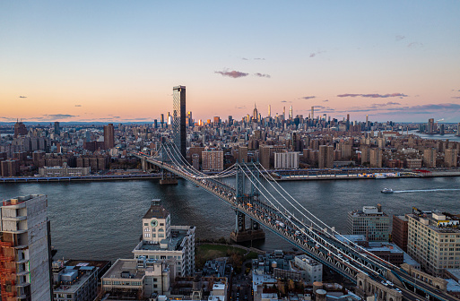 Famous cable stayed Manhattan bridge over East River at twilight. Urban boroughs and downtown skyscrapers in distance. Manhattan, New York City, USA.