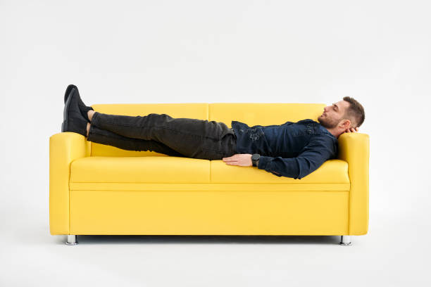 istock Young man relaxing alone on yellow sofa at home 1405848897