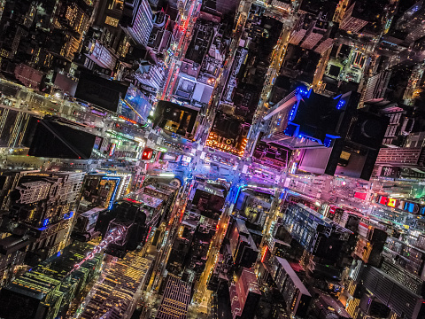 Overhead shot of buildings and streets around Times Square. Advertisements and displays glowing colourful light. Manhattan, New York City, USA.