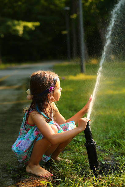 istock Happy girl playing with a water sprinkler 1405852023