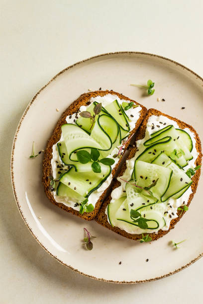 istock Breakfast, cereal bread sandwiches, cream cheese, sliced cucumber, with micro greenery on a light table, close-up, top view, selective focus, no people, 1405853824