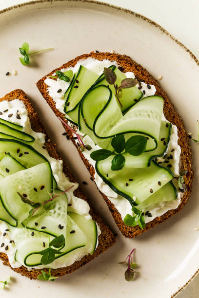 istock Breakfast, cereal bread sandwiches, cream cheese, sliced cucumber, with micro greenery on a light table, close-up, top view, selective focus, no people, 1405853825