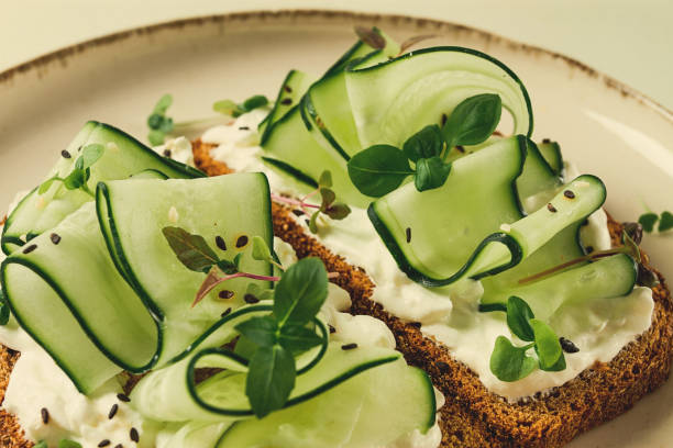 istock Breakfast, cereal bread sandwiches, cream cheese, sliced cucumber, with micro greenery on a light table, close-up, top view, selective focus, no people, 1405853834