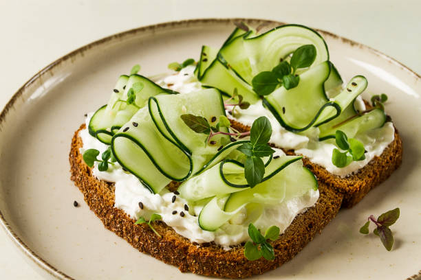 istock Breakfast, cereal bread sandwiches, cream cheese, sliced cucumber, with micro greenery on a light table, close-up, top view, selective focus, no people, 1405853839