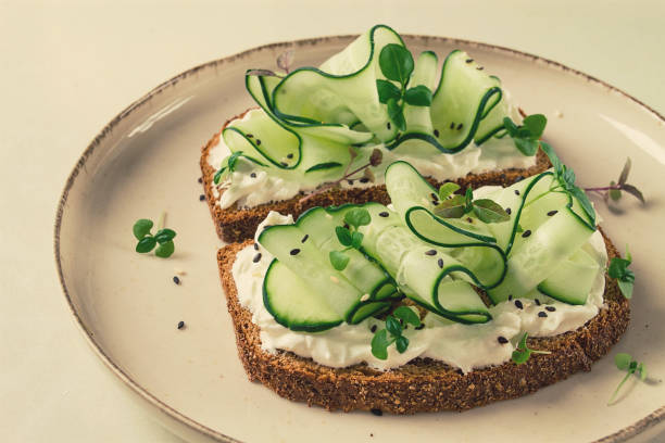 istock Breakfast, cereal bread sandwiches, cream cheese, sliced cucumber, with micro greenery on a light table, close-up, top view, selective focus, no people, 1405854168
