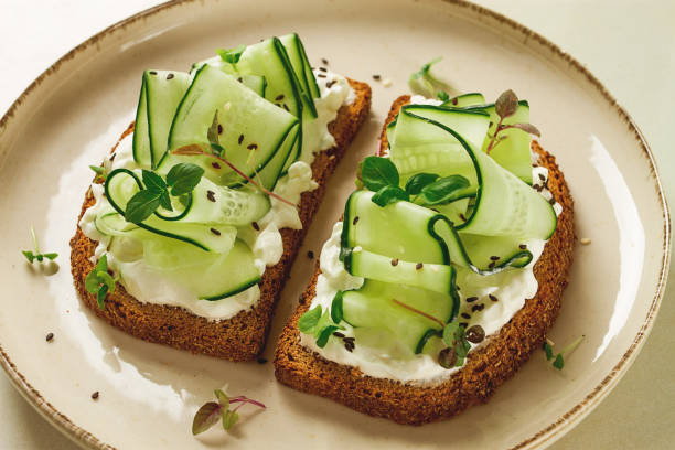 istock Breakfast, cereal bread sandwiches, cream cheese, sliced cucumber, with micro greenery on a light table, close-up, top view, selective focus, no people, 1405854169